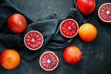 Flat lay food composition with blood oranges on a dark blue background.