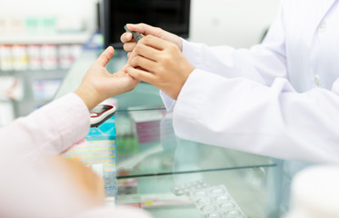 asian healthcare worker use glucometer screening patient in hospital, pharmacist holding hand of...