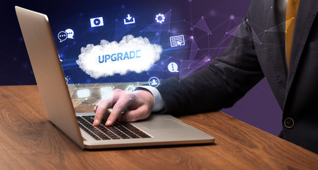 Businessman working on laptop with UPGRADE inscription, modern technology concept