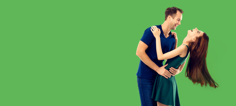 Love, relationship, dating, flirting, lovers, romantic concept - full body portrait of hugging or dancing couple, looking at each other. Green color background.