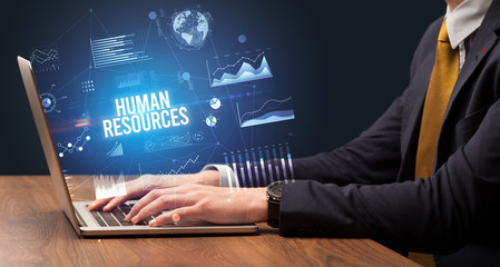 Businessman working on laptop with HUMAN RESOURCES inscription, new business concept