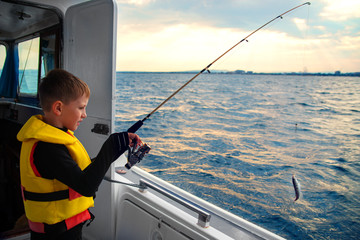 little boy caught fish spinning from a boat at sea