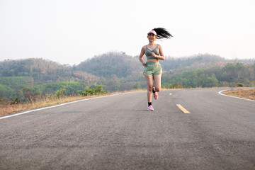Obraz premium Photo fone view Asia young smiling woman runner running on asphalt road