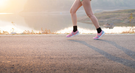 Photo front view Sporty Asia young woman wear sports shoes running on asphalt road