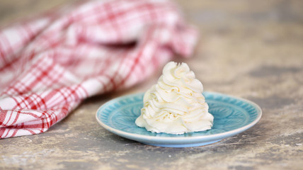 Whipped cream on blue plate, close-up. Vanilla cream