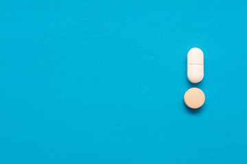 Pills in the form of an exclamation mark on a blue background.