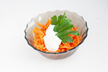 Grated carrots in a bowl with parsley and sour cream