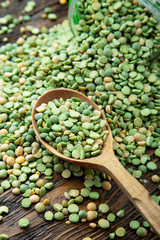 Homemade green peas in a wooden spoon on a wooden surface.