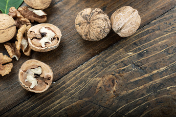 Whole and chopped walnuts  on wooden background.