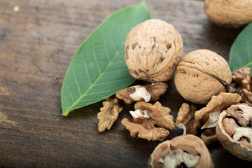 Whole and chopped walnuts  on wooden background.