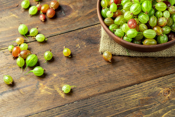 Ripe gooseberry in a clay plate, place for text, top view.