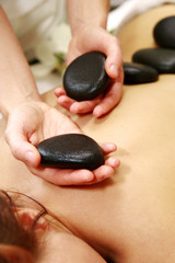 Cropped view of young woman having stone therapy at massage salon