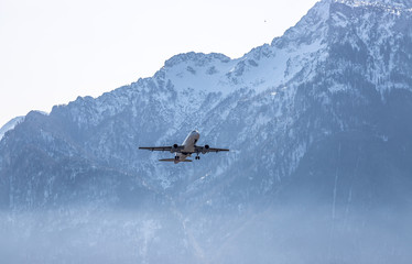 Airplane scenery:  take off from airport, mountain range in the alps. Travel by air, transportation