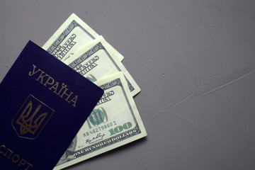 Ukrainian passport with dollar bills on a concrete background. The passport printed "Passport of Ukraine".