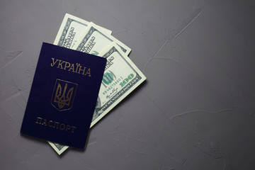 Ukrainian passport with dollar bills on a concrete background. The passport printed 