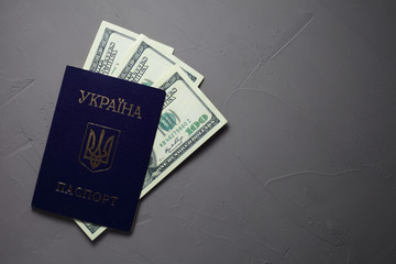 Ukrainian passport with dollar bills on a concrete background. The passport printed "Passport of Ukraine".