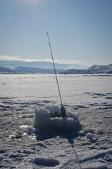 The lone fishing pole out in the frozen lake bed.