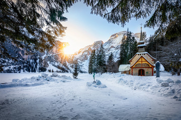 Beautiful Alpine winter landscape with a little church in the snow and morning sunrise at  Lago di Braies also called Pragser Wildsee, Italy