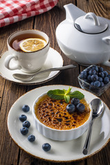 Creme brulee decorated with blueberries and mint leaves