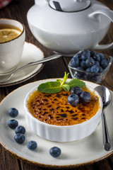Creme brulee decorated with blueberries and mint leaves