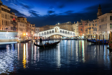  Die beleuchtete Rialto Brücke in Venedig, Italien, mit vorbeifahrender Gondel bei Nacht