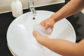 Man washing hands with soap under running water