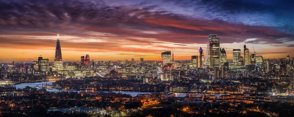 Fototapeten Weites Panorama der beleuchteten Skyline von London am Abend mit den Wolkenkratzern der City und zahlreichen Touristen Attraktionen, Großbritannien © moofushi