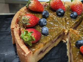 Deliciously sweet passion fruit pie with fresh strawberry and blueberry on toping.