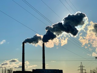 Smoke from industrial chimneys against a blue sky. Smoke from factory chimneys in an urban environment. Concept: environmental pollution.