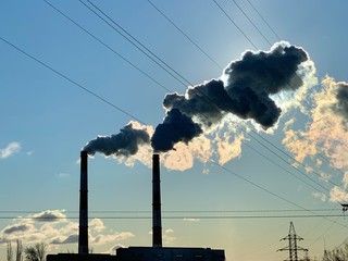 Smoke from industrial chimneys against a blue sky. Smoke from factory chimneys in an urban...