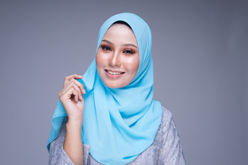 Headshot of a beautiful female model poses wearing modern kebaya and hijab, a urban lifestyle apparel for Muslim women isolated on grey background. Beauty and hijab fashion concept.