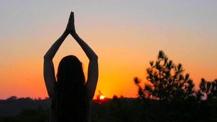 Une femme fait du yoga devant un coucher de soleil