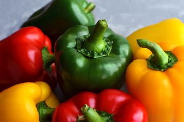 Green, red and yellow bell pepper on grey stone background. Organic healthy food