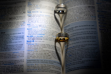 Valentine hearts on a dictionary page drawn by shadow of two rings  and definition of love