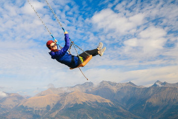 girl on a swing in the mountains is engaged in extreme sports