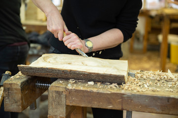 Frau schnitzt etwas aus einem Stück Holz