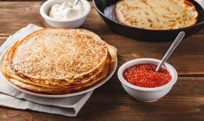 Stack of russian pancakes blini with red caviar, fresh sour cream