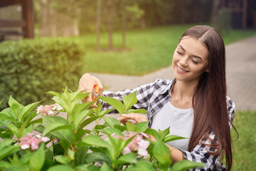 Young smiling woman pruning bushes.