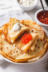 Stack of russian pancakes blini with red caviar, fresh sour cream
