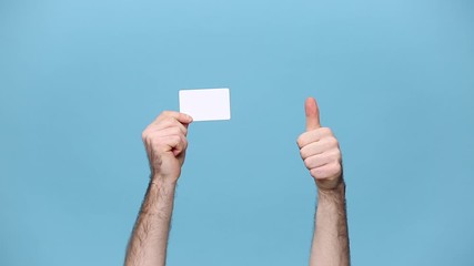 Close up cropped male hold in hand plastic empty credit bank card isolated on pastel blue background background. Finance design, currency concept. Copy space Mock up. Advertising area. Online shopping