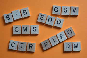Business acronyms in 3d wooden alphabet letters on orange background