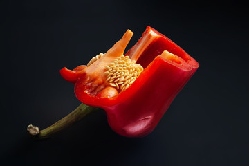 Red sweet pepper with seeds. Cutting bell peppers on a black background. Organic food.