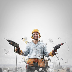 Construction worker in dirty clothes with a hammer and drill at work
