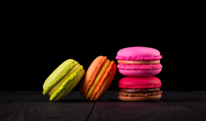 Heap of french colorful macaroons on wooden table isolated on black