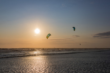 2 surfers, in the background the sunset, a surfer jumps high