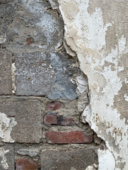 cinder block wall whose concrete layer cracks and disappears