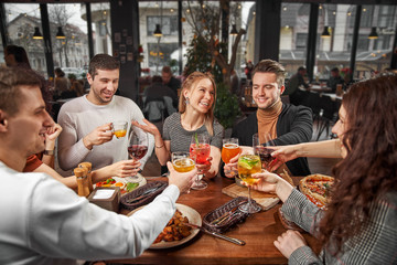 Fototapeta na wymiar Happy multiracial young friends relax together talking laughing sit at cafe table, cheerful diverse students girls and guys people group studying having fun indoor, multicultural friendship concept
