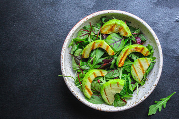 healthy salad grilled avocado and green leaves (vegetarian or diet food) menu concept background. top view. copy space