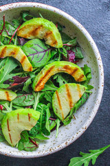 healthy salad grilled avocado and green leaves (vegetarian or diet food) menu concept background. top view. copy space