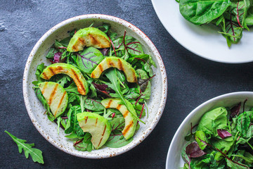 healthy salad grilled avocado and green leaves (vegetarian or diet food) menu concept background. top view. copy space